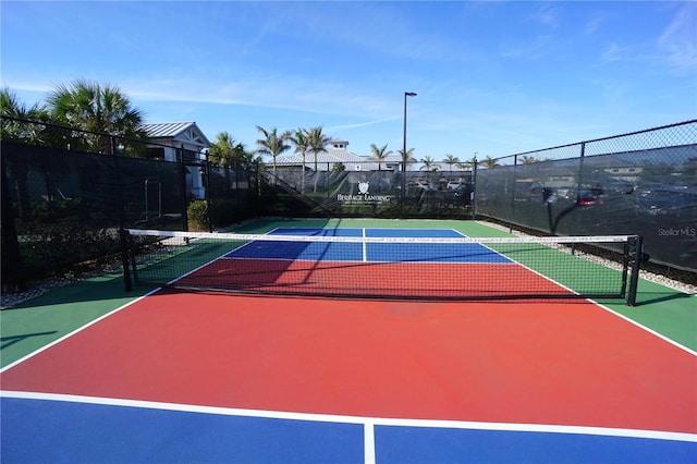 view of tennis court featuring community basketball court and fence