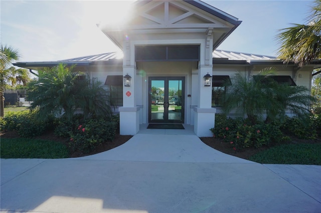 property entrance with metal roof, french doors, a standing seam roof, and stucco siding