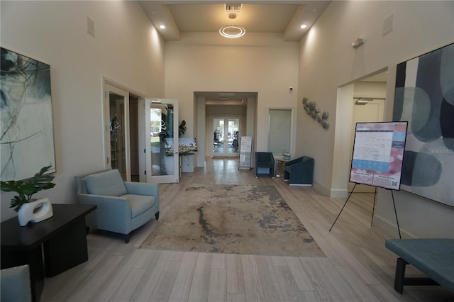 interior space featuring french doors, visible vents, a towering ceiling, light wood-style floors, and baseboards