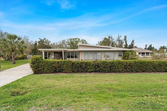 ranch-style home featuring an attached carport, driveway, and a front lawn