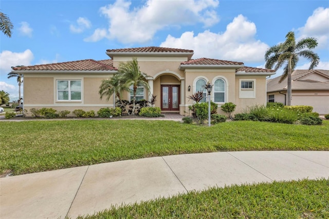 mediterranean / spanish home with a front yard, french doors, a tile roof, and stucco siding