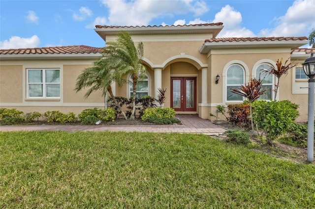 doorway to property featuring a yard, stucco siding, and french doors