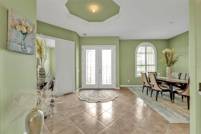 tiled foyer entrance with baseboards, a tray ceiling, and french doors