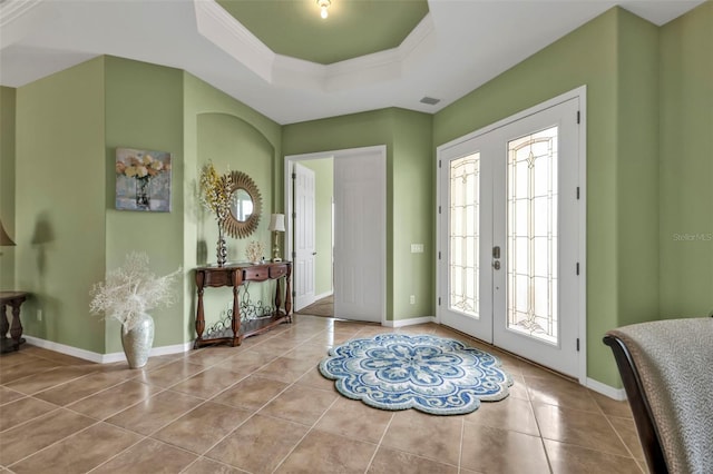 tiled foyer entrance with crown molding, french doors, a raised ceiling, and baseboards