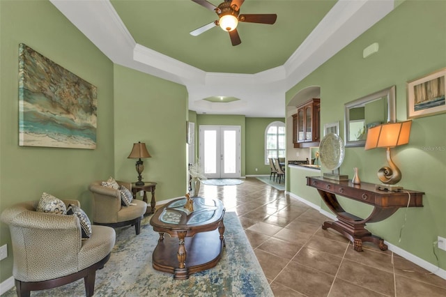 living area featuring tile patterned flooring, baseboards, ornamental molding, french doors, and a raised ceiling