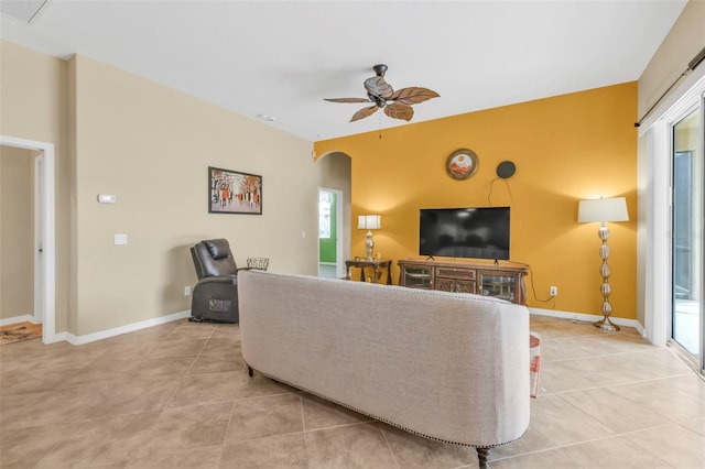 living room with arched walkways, ceiling fan, light tile patterned flooring, visible vents, and baseboards