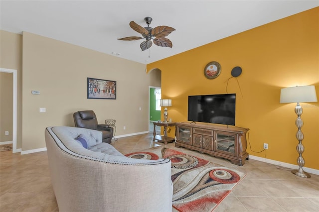 living room featuring a ceiling fan, arched walkways, tile patterned flooring, and baseboards