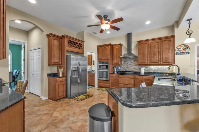 kitchen featuring stainless steel appliances, a peninsula, a sink, wall chimney range hood, and backsplash