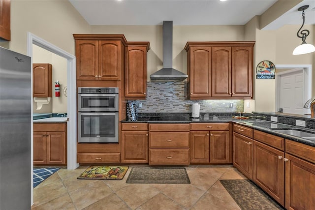 kitchen featuring wall chimney exhaust hood, backsplash, a sink, and stainless steel appliances