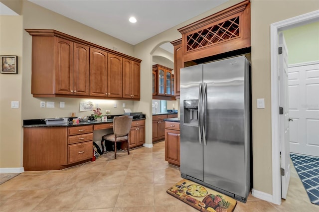 kitchen featuring recessed lighting, baseboards, stainless steel fridge with ice dispenser, brown cabinetry, and dark countertops