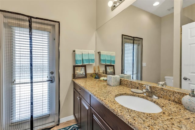 bathroom with plenty of natural light, vanity, toilet, and tile patterned floors