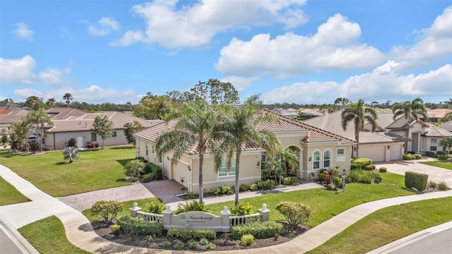 mediterranean / spanish-style home with a front lawn, an attached garage, a tile roof, and a residential view