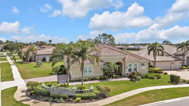 mediterranean / spanish home with an attached garage, a tiled roof, a front lawn, and stucco siding