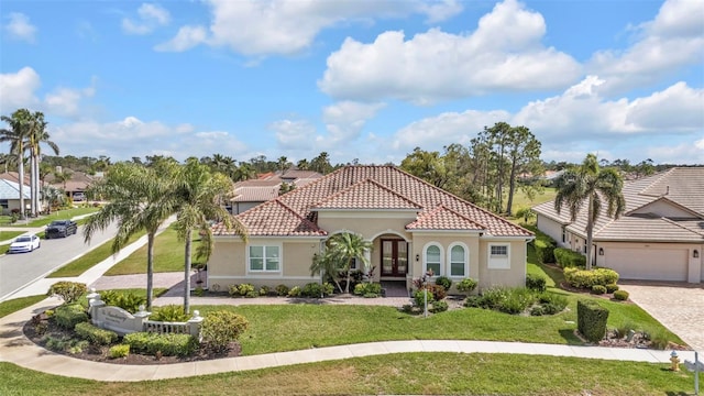 mediterranean / spanish house with french doors, a tiled roof, a front lawn, and stucco siding