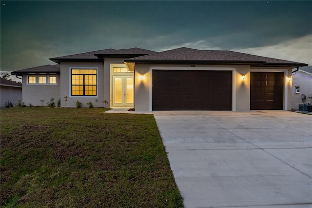 prairie-style home featuring a garage, driveway, french doors, stucco siding, and a front yard