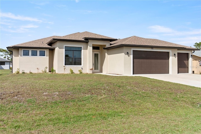 prairie-style house featuring a garage, driveway, a front lawn, and stucco siding