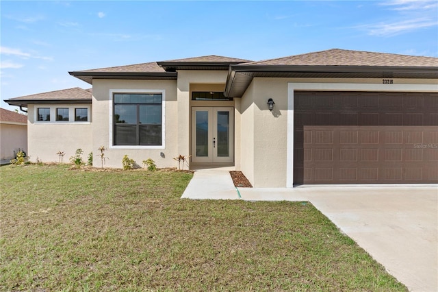 prairie-style home with an attached garage, french doors, a front yard, and stucco siding