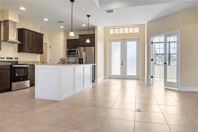 kitchen with wall chimney exhaust hood, french doors, appliances with stainless steel finishes, and dark brown cabinetry