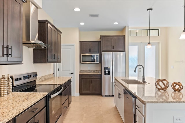 kitchen with stainless steel appliances, a sink, visible vents, dark brown cabinets, and wall chimney exhaust hood