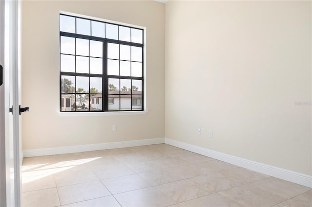 empty room with baseboards and light tile patterned flooring