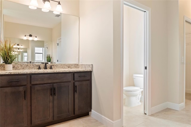 bathroom featuring toilet, vanity, visible vents, and baseboards