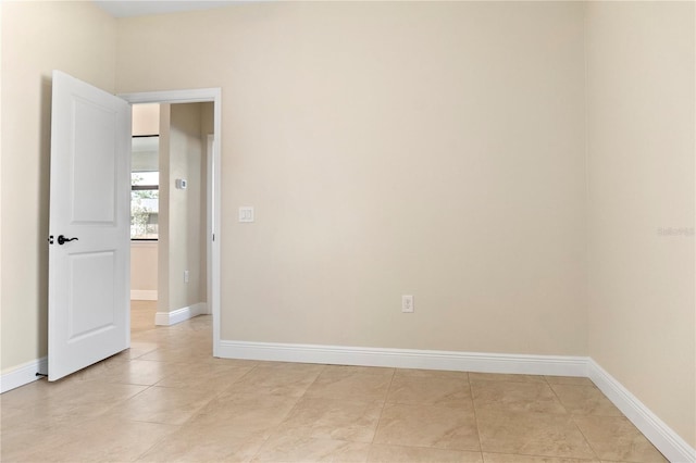 empty room with light tile patterned floors and baseboards