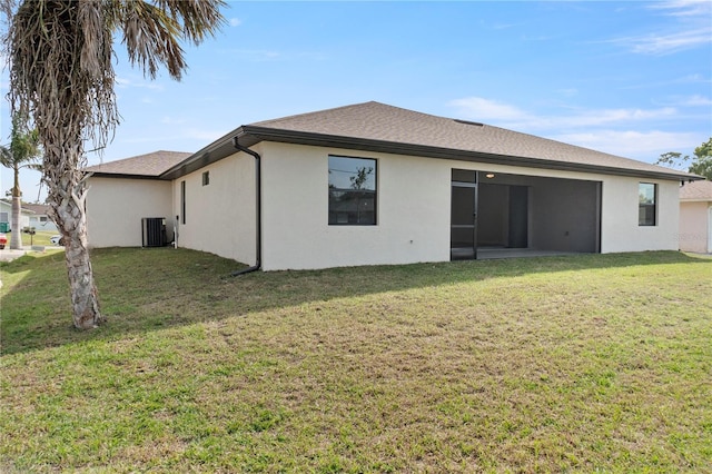 rear view of property with central AC, a shingled roof, a lawn, and stucco siding