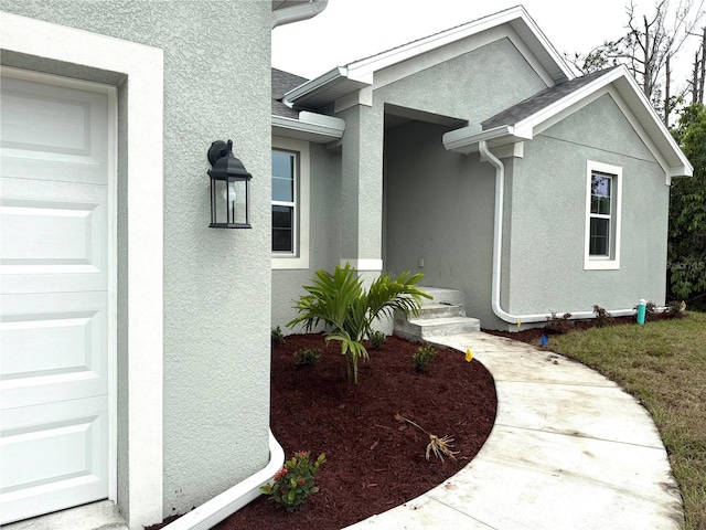 9590 Little Rock St, Port Charlotte, FL 33981 - doorway to property with stucco siding, roof with shingles, and an attached garage