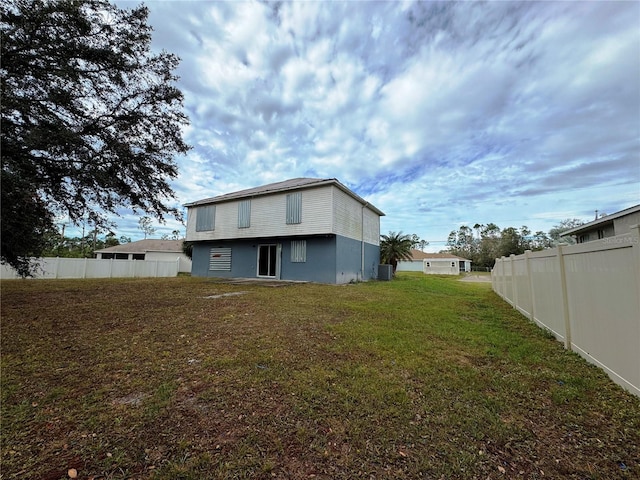 back of property with a yard, a fenced backyard, and central air condition unit