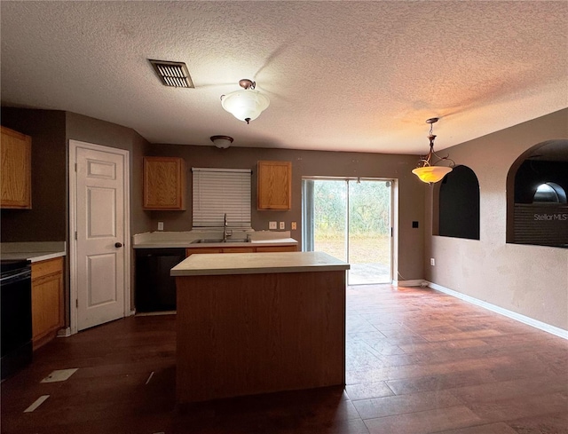 kitchen featuring visible vents, dishwasher, a kitchen island, hanging light fixtures, and light countertops