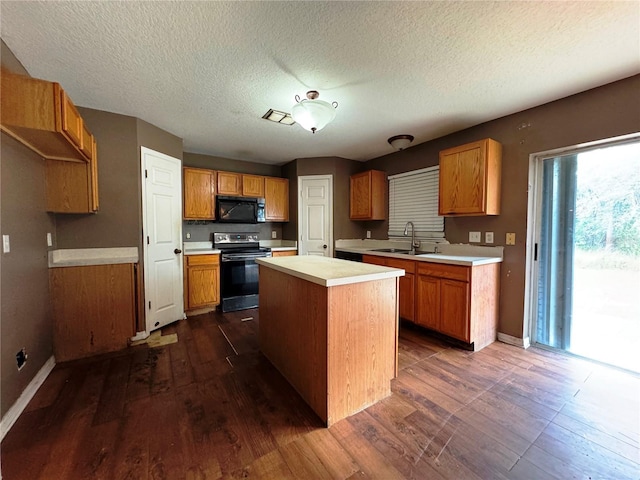 kitchen featuring black microwave, a sink, electric stove, light countertops, and a center island