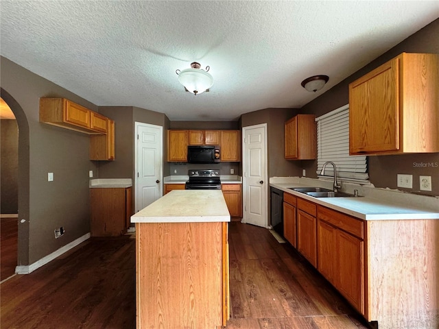 kitchen with arched walkways, light countertops, a kitchen island, a sink, and black appliances