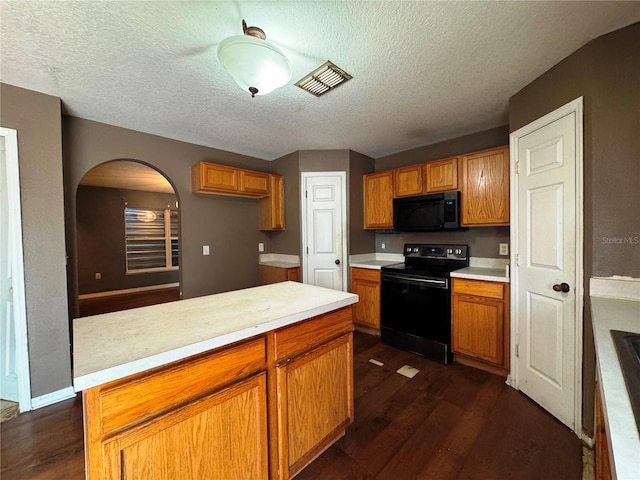 kitchen with dark wood-style floors, a center island, brown cabinets, light countertops, and black appliances