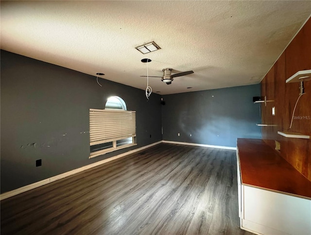 unfurnished living room featuring baseboards, visible vents, dark wood finished floors, and a textured ceiling