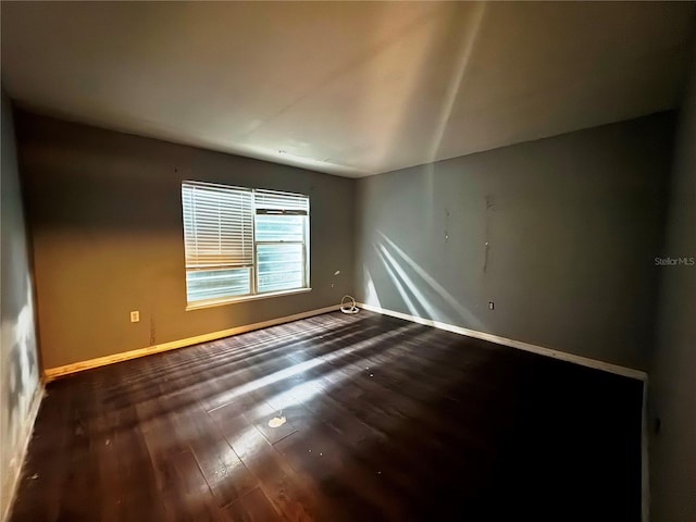 spare room with dark wood finished floors and baseboards