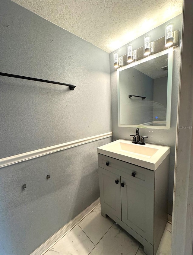 bathroom with a textured ceiling, marble finish floor, a textured wall, and vanity