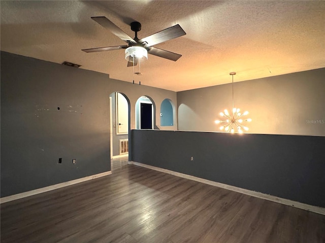 unfurnished room with visible vents, baseboards, dark wood-style flooring, a textured ceiling, and ceiling fan with notable chandelier