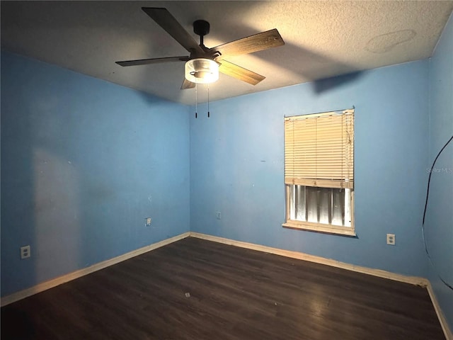 empty room with dark wood finished floors, a textured ceiling, baseboards, and ceiling fan