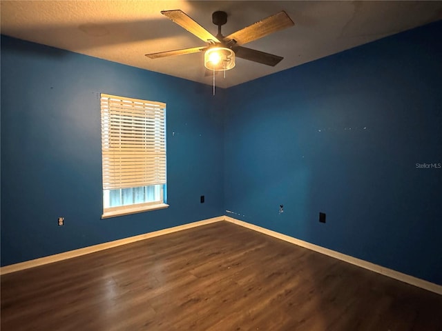 empty room with ceiling fan, a textured ceiling, baseboards, and wood finished floors