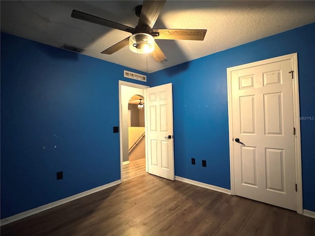 unfurnished bedroom featuring dark wood-style floors, visible vents, and baseboards