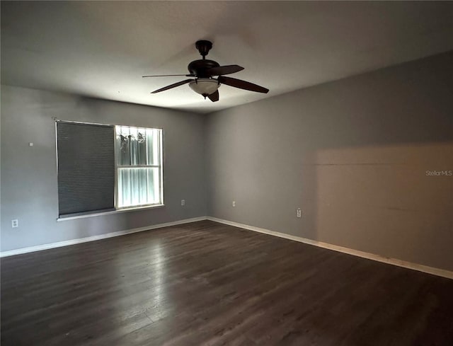 unfurnished room with dark wood-style floors, ceiling fan, and baseboards