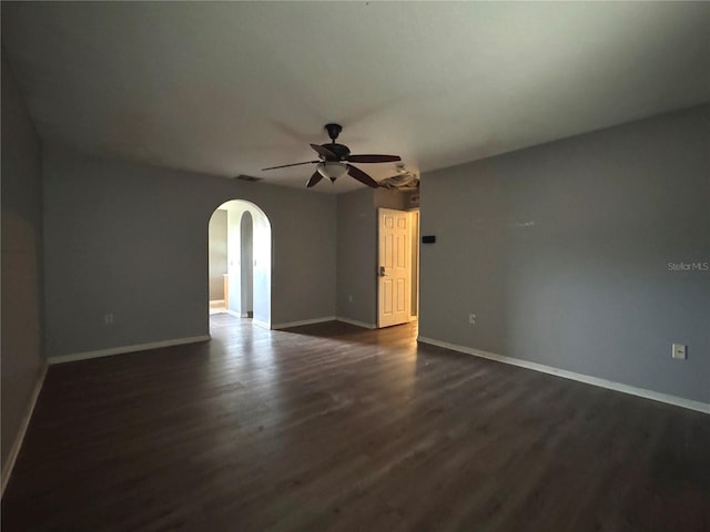 spare room with arched walkways, dark wood-style floors, visible vents, and baseboards