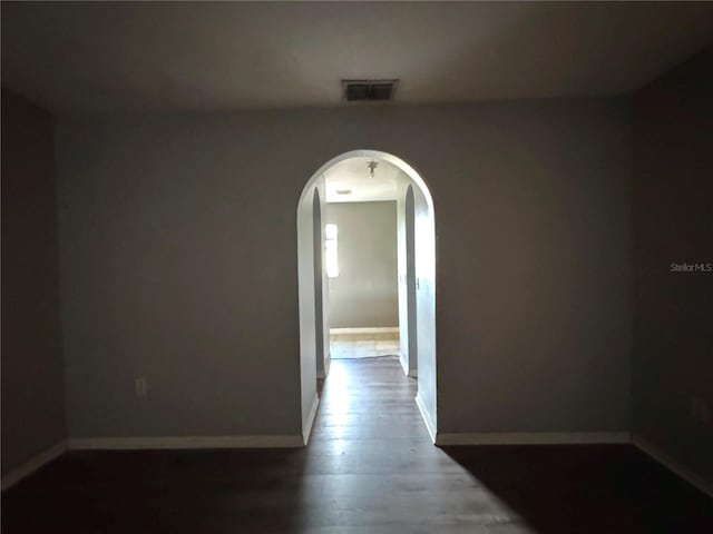 hallway with arched walkways, visible vents, and baseboards