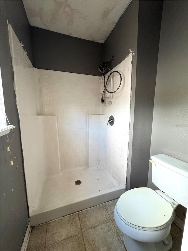 bathroom with a shower stall, toilet, and tile patterned floors