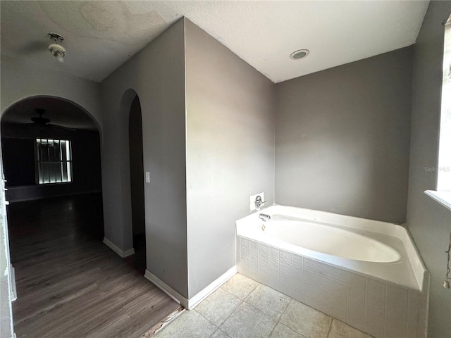 full bathroom with a bath and baseboards