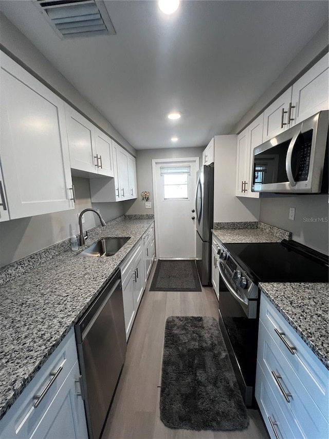 kitchen featuring light wood finished floors, visible vents, white cabinets, stainless steel appliances, and a sink