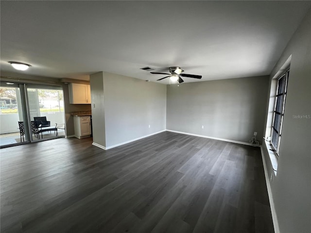 unfurnished living room featuring a ceiling fan, visible vents, baseboards, and dark wood-type flooring