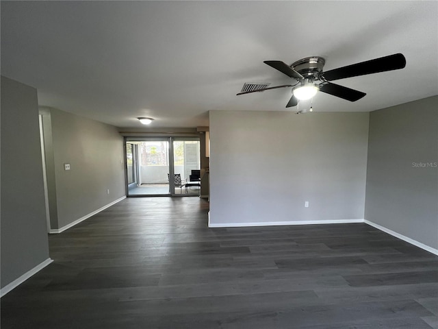 spare room with a ceiling fan, dark wood finished floors, visible vents, and baseboards