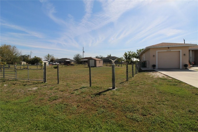 view of yard with a garage, a storage shed, concrete driveway, fence, and an outdoor structure