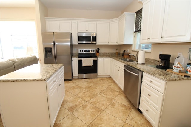 kitchen featuring appliances with stainless steel finishes, white cabinetry, and light stone countertops